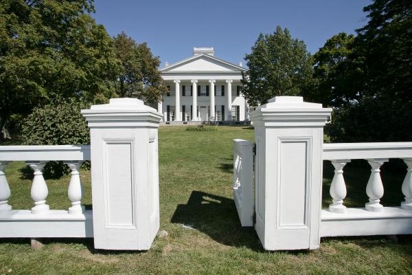 white-columned-building-viewed-across-a-lawn-from-a-gate