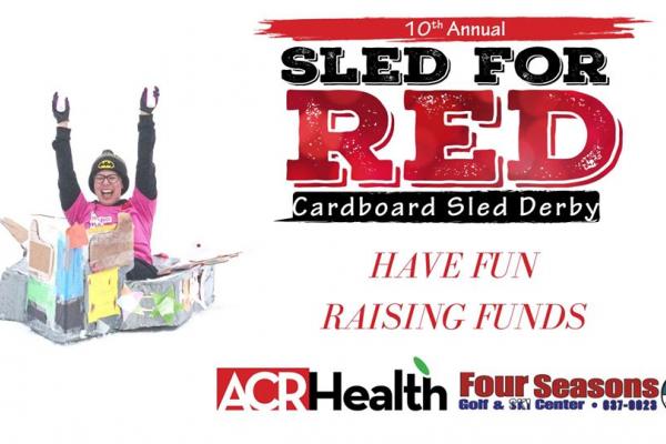 10th Annual sled of red cardboard sled Derby with ACR Health: Girl sledding in cardboard